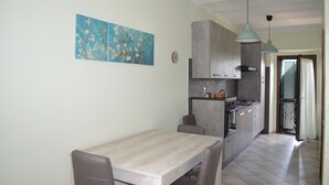 Una cocina moderna con armarios grises, una mesa de comedor de madera e iluminación colgante.