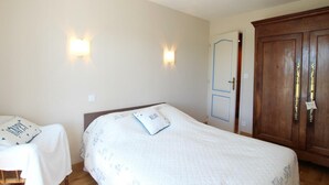 A bedroom with two beds, a wardrobe, and two wall-mounted lights. - Family Home with Garden Near Mont St Michel - 3BR, 2BA, WiFi, Baby Gear, Linens Included (Céaux)