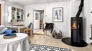 Ein gemütliches Wohnzimmer mit Kamin, Bücherregal, Essbereich und einer Treppe zu einer weiteren Ebene.