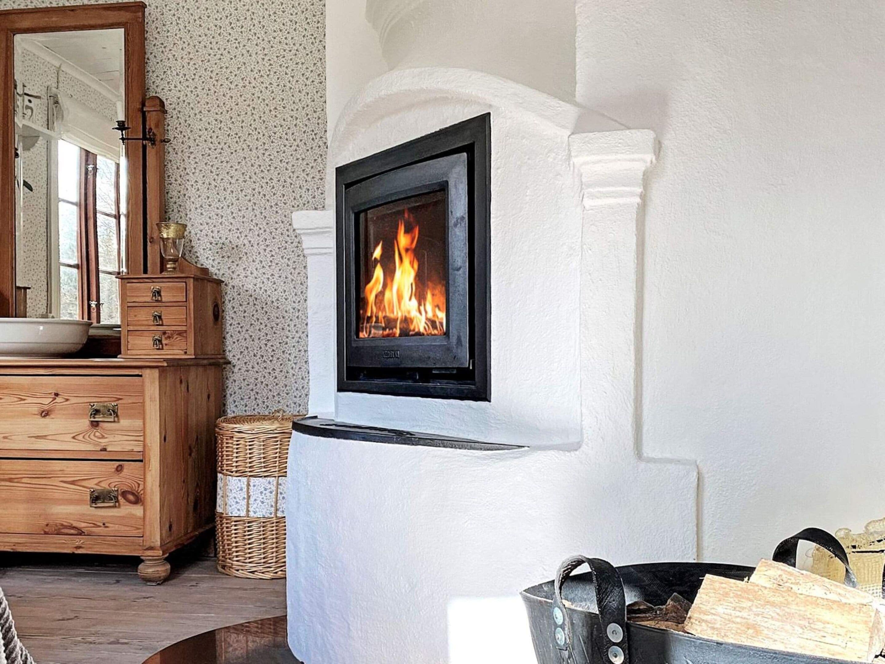 Une cheminée au design moderne, une commode en bois et un miroir.