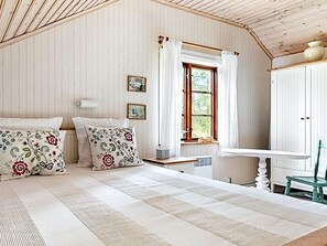 A bedroom with a bed, a window with curtains, a bedside table, and a chair. - 4 Star Holiday Home in Skillingaryd (Skillingaryd)
