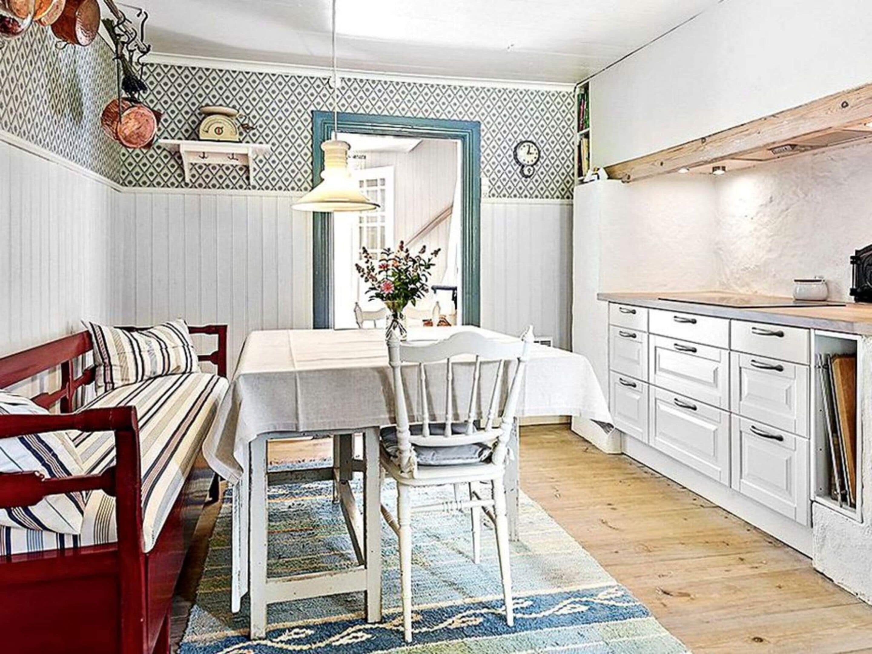 A dining area with a table, chairs, a bench, and a kitchen area with cabinets and a countertop.