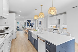 A modern kitchen with white cabinets, a large island, and pendant lighting.