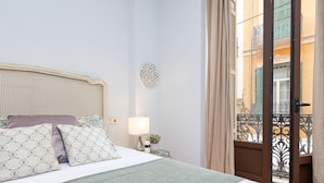 Un lit bien fait, agrémenté d’oreillers à motifs, d’une lampe de chevet et d’un élément décoratif mural.