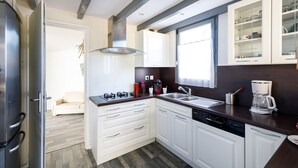 Una cocina moderna con armarios blancos, estufa a gas, un lavamanos y una cafetera.