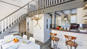 Una cocina moderna con barra, armarios blancos y una escalera que sube a otro nivel.