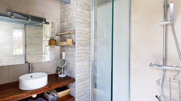 A modern bathroom with a large mirror, a white sink, and a glass-enclosed shower.