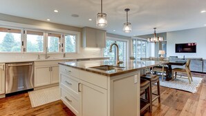 Una cocina moderna con una isla central, electrodomésticos de acero inoxidable e iluminación colgante.