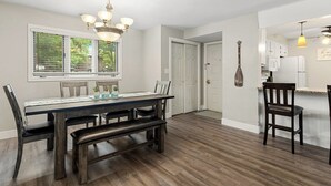 A dining area with a wooden table, benches, and a chandelier. - Knolls 0424 - Three Bedroom Apartment, Sleeps 8 (Osage Beach)