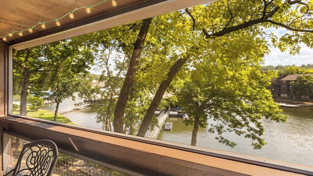 A view from a window overlooking a river, trees, and a bridge. - Knolls 0424 - Three Bedroom Apartment, Sleeps 8 (Osage Beach)
