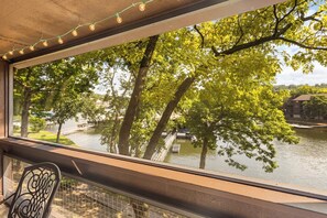 Vista desde una ventana sobre un río, árboles y un puente.