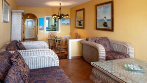 A living room with two sofas, a glass coffee table, and a dining table with chairs. - Casa La Isleta     . (Níjar)