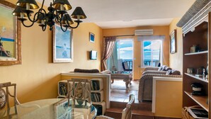 A spacious living area with a glass dining table, wicker chairs, a sofa, and a balcony with a view. - Casa La Isleta     . (Níjar)