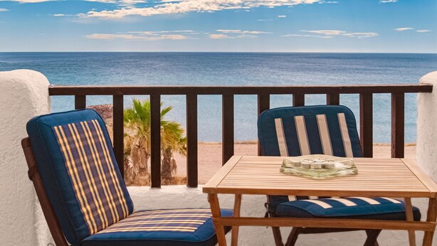 A balcony with two chairs and a table, overlooking a beach and the sea. - Casa La Isleta     . (Níjar)