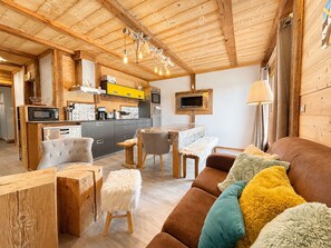Ein gemütliches Interieur mit Holzbalken, einer Küche mit modernen Geräten, einem Essbereich und einer bequemen Sitzecke.