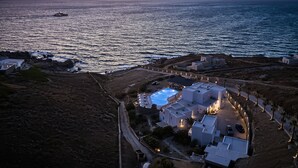 A coastal property with a swimming pool, white buildings, and a view of the sea at sunset. - Ubud Mykonos (Mykonos)