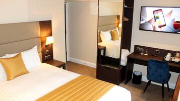 Une chambre d’hôtel équipée d’un lit, d’un bureau, d’une chaise, d’une télévision et d’une poubelle.