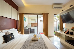 A hotel room with a bed, a TV, a desk, and a view of the outside.