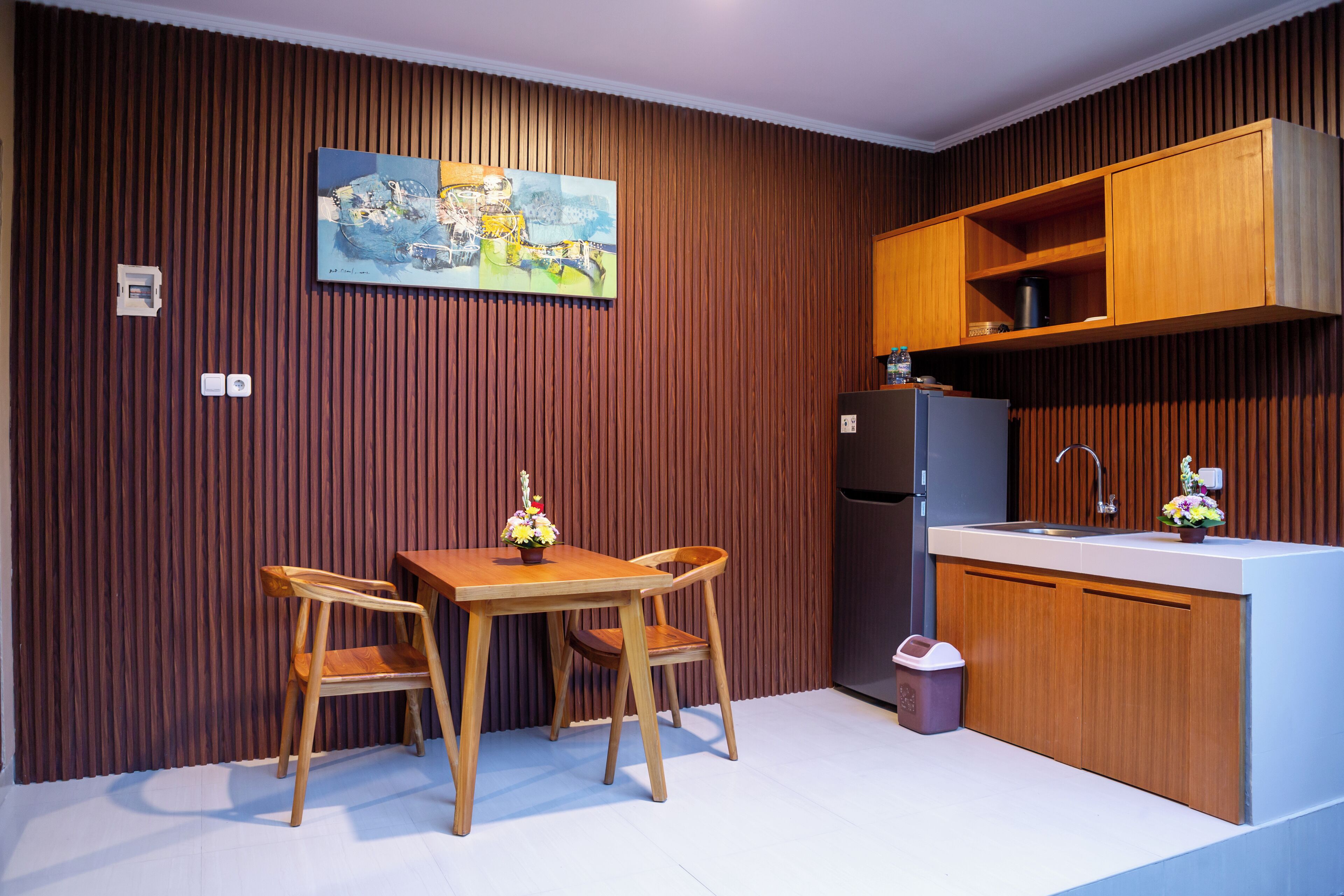 Una cocina moderna con armarios de madera, una mesa de comedor con sillas, un refrigerador y un fregadero.