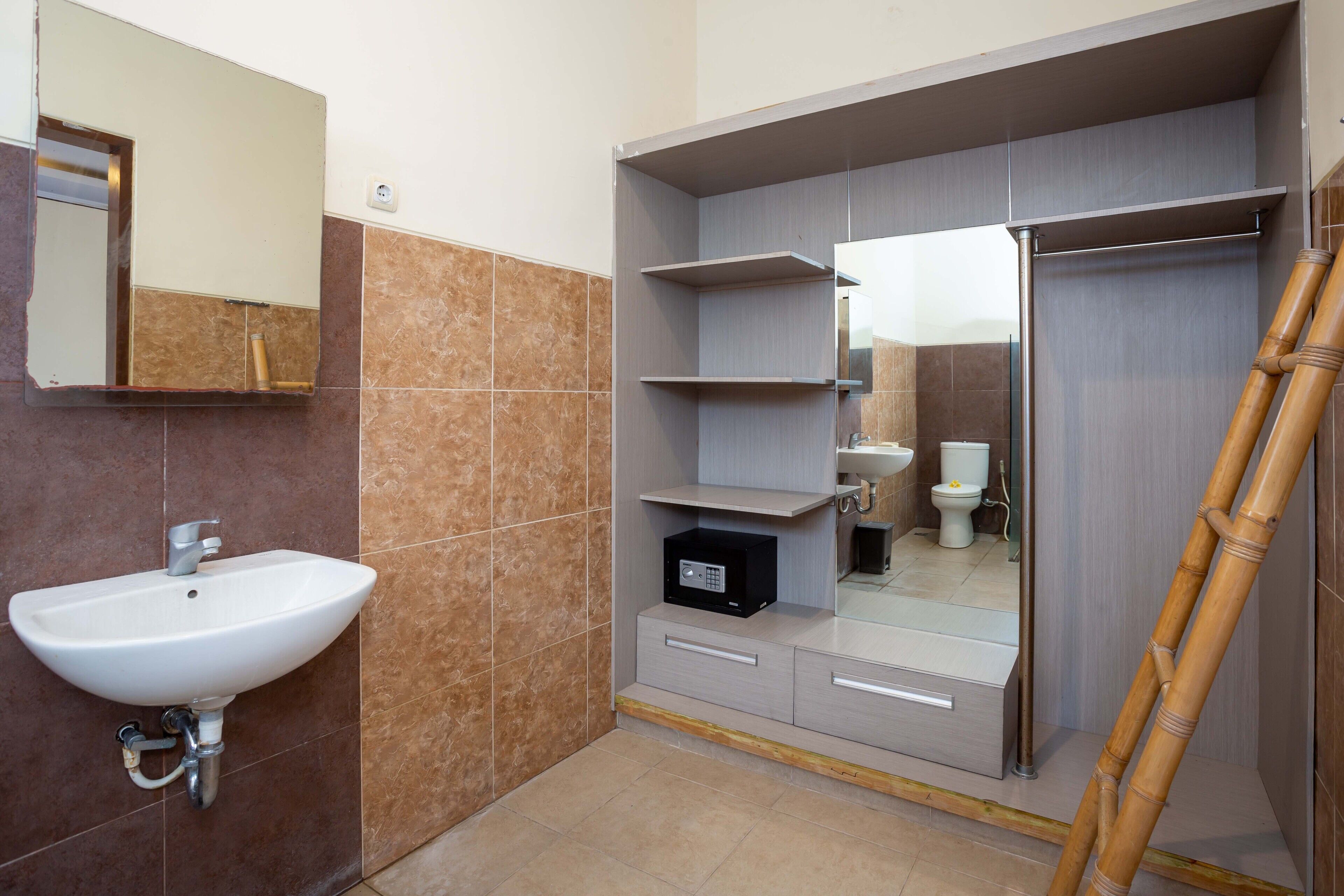 Une salle de bain avec un lavabo blanc, un miroir et des étagères.