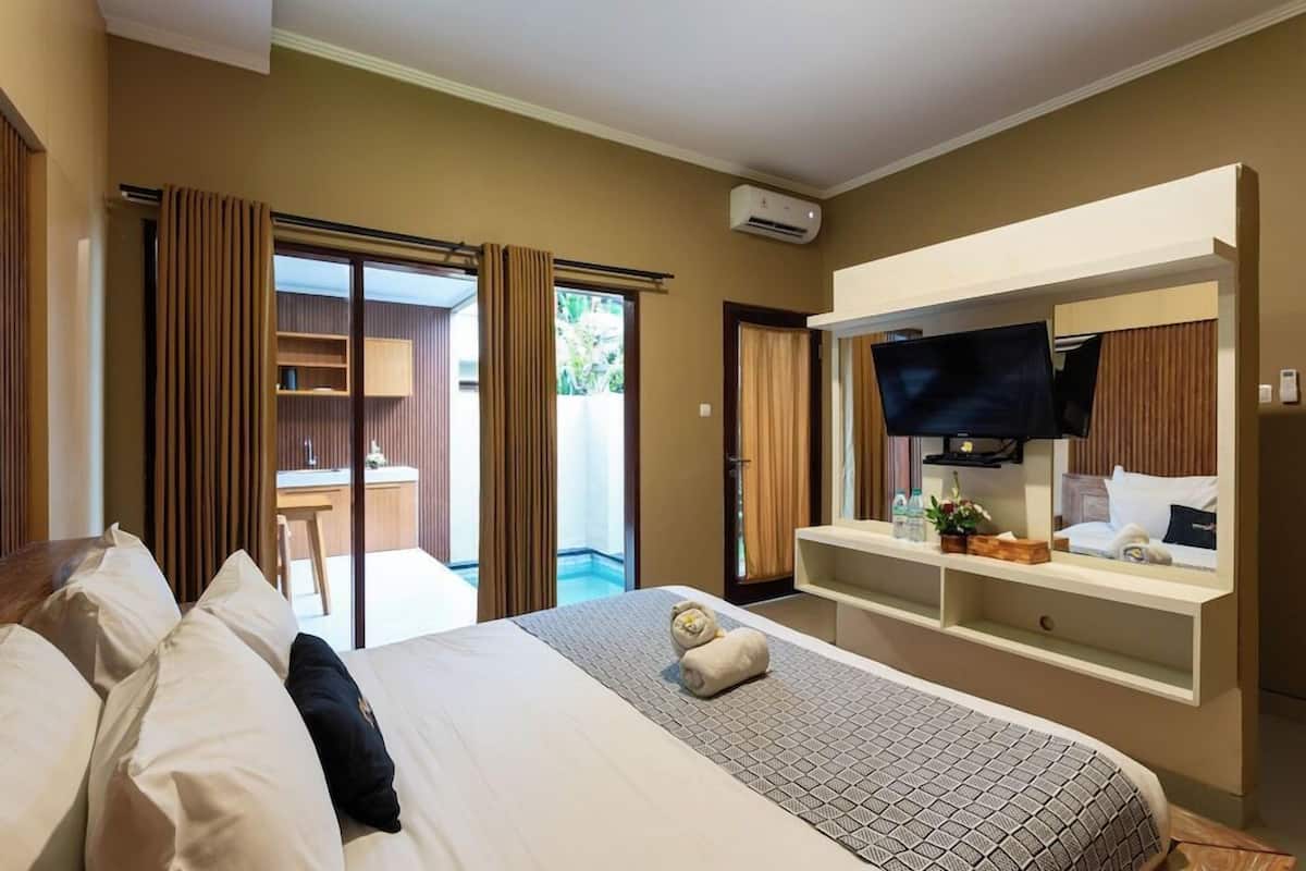 A hotel room with a bed, a TV, a desk, and a balcony.