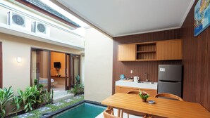 A modern kitchen with wooden cabinets, a black refrigerator, and a dining area with a wooden table and chairs. - Karana Villa Bali (Denpasar)