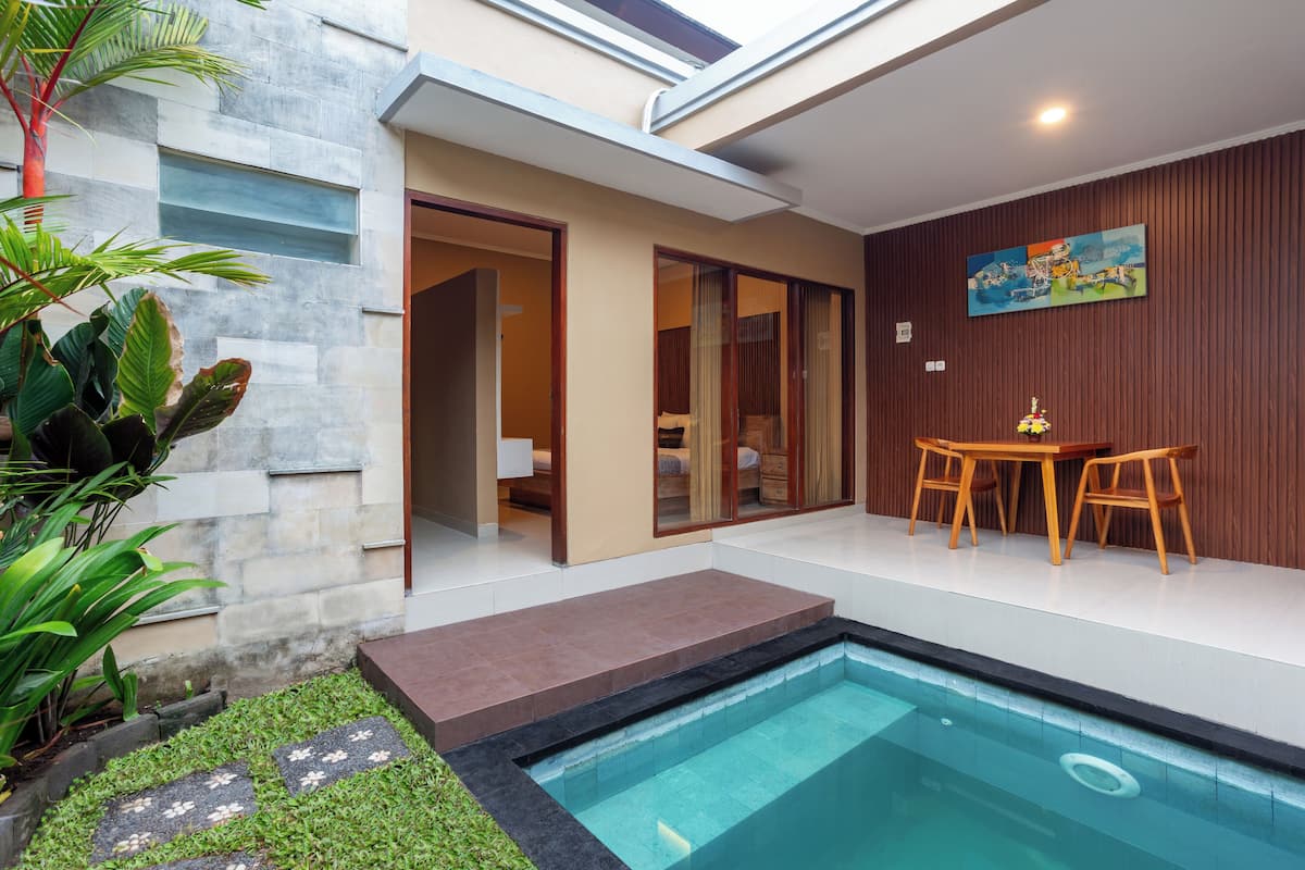 A modern outdoor pool area with a stone wall, a wooden deck, and a dining set.
