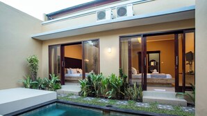 A modern hotel with a swimming pool, large sliding glass doors, and a well-maintained garden area. - Karana Villa Bali (Denpasar)