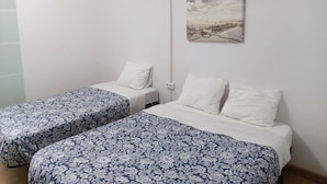 Una habitación con dos camas individuales, un cuadro de un paisaje y un equipo de aire acondicionado blanco.