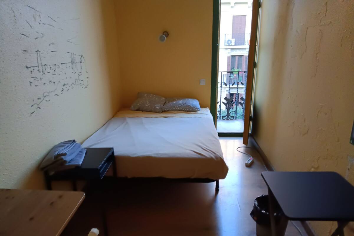 Ein schmaler Raum mit einem Bett, einem Schreibtisch und einem Stuhl.