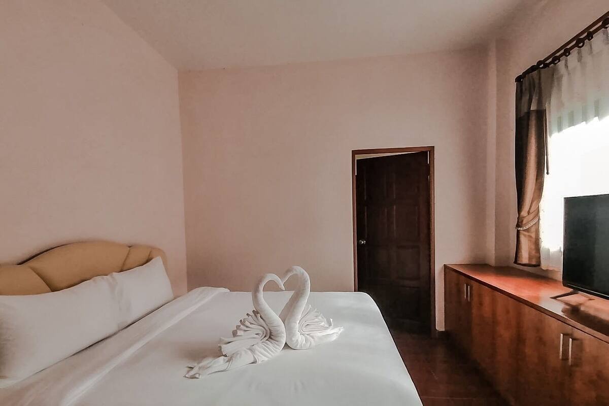 A hotel room with a bed, a wooden cabinet, a television, and a door.