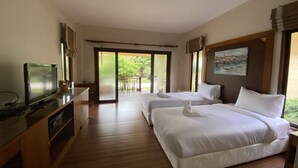 A hotel room with two beds, a TV, and a balcony with a view of greenery. - Chaithalay Khanom Resort (Khanom)