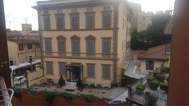 A multi-story building with a central entrance, a small staircase leading to the entrance, and a gated area with potted plants. - Florence Hostels Anamaria (Florence)