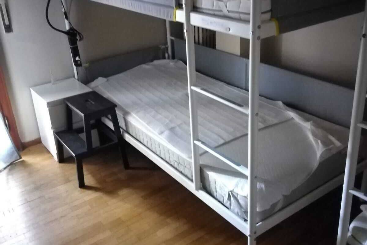 A bunk bed with a desk and a green bag on the top bunk.
