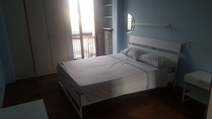 A bedroom with a bed, a bedside table, a wardrobe, and a window with a view. - Florence Hostels Anamaria (Florence)