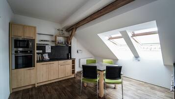 Une cuisine compacte avec des meubles en bois, un four à micro-ondes encastré et une table à manger avec des chaises.