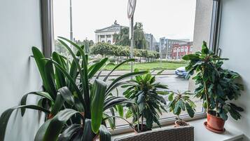 A view from a window with potted plants, a street sign, and buildings in the background.