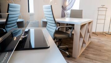 Un espacio de oficina moderno con un escritorio blanco, dos sillas ergonómicas y una computadora portátil.
