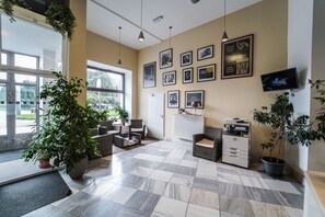 Moderni sisustus, jossa on ruutukuviollinen lattia, oleskelualue, suuret ikkunat ja seinälle asennettuja taideteoksia.