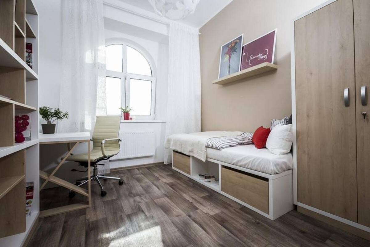 A room with a bed, a desk, and a window.