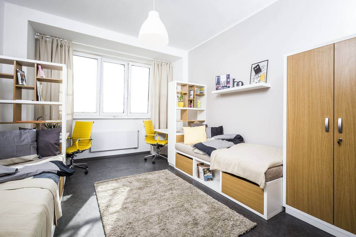 A modern bedroom with a bed, a desk, a chair, and built-in shelving.
