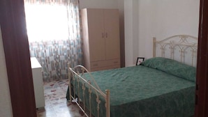 Een slaapkamer met een bed, een kledingkast en een raam met gordijnen.