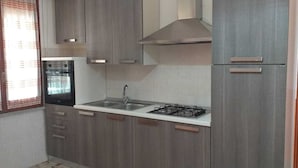 Een kleine keuken met een gasfornuis, een spoelbak en een ingebouwde oven.