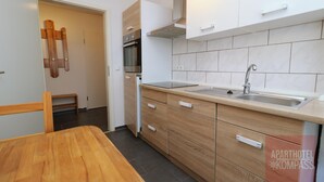 Une cuisine moderne avec des meubles en bois, un four encastré et un évier en acier inoxydable.