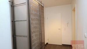 Un couloir avec une porte coulissante et une porte fermée.