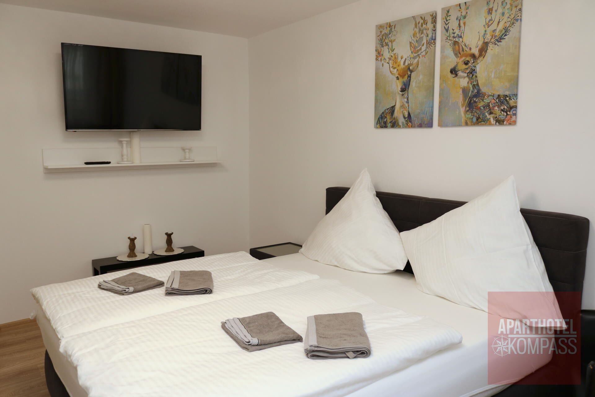 Une chambre d’hôtel avec un lit, une télévision, une table de chevet et des œuvres d’art accrochées au mur.
