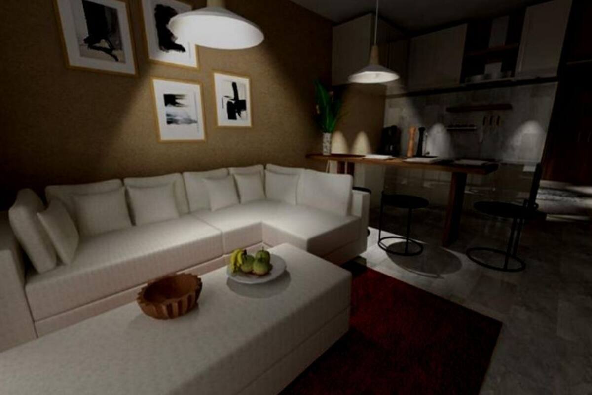 A modern living room with a sofa, a coffee table with fruit, and a kitchen area in the background.