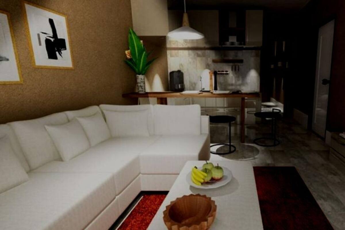 A modern living room with a white sofa, a coffee table with fruits, a TV, and a kitchen in the background.