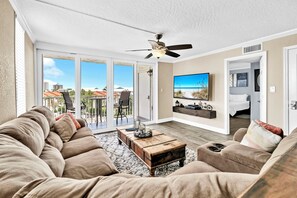 A spacious living room with a large sectional sofa, a wooden coffee table, and a ceiling fan. - Renovated 2 Bedroom 2 Bath on the Harbor (Destin)