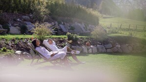 A person relaxing in a chair outdoors with a mountainous backdrop. - Eden Boutique Hotel (Curon Venosta)